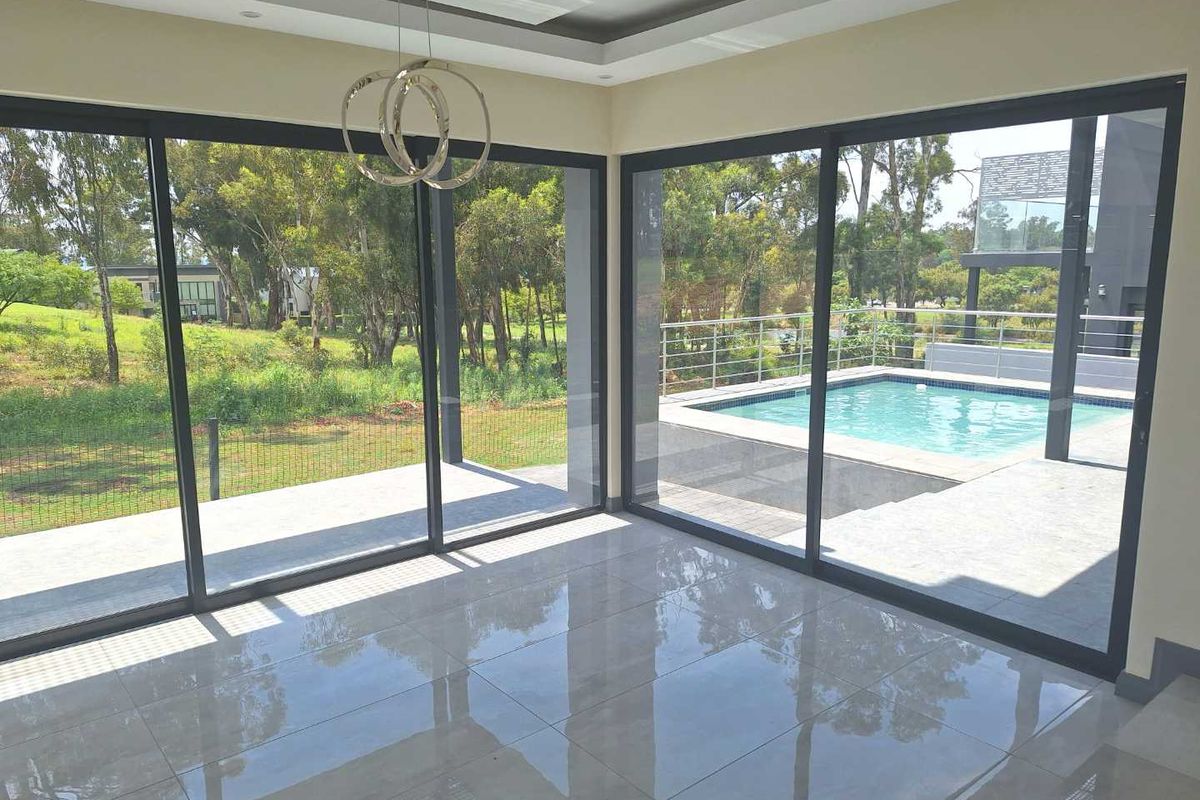 Bright, modern living area featuring large format floor tiles, recessed ceiling lighting, and expansive sliding doors opening onto a private pool deck.