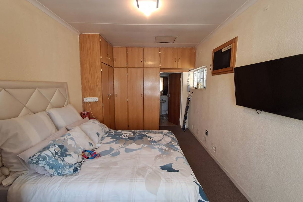A bedroom featuring built-in wooden cupboards, carpeted flooring, and an en-suite bathroom access point.