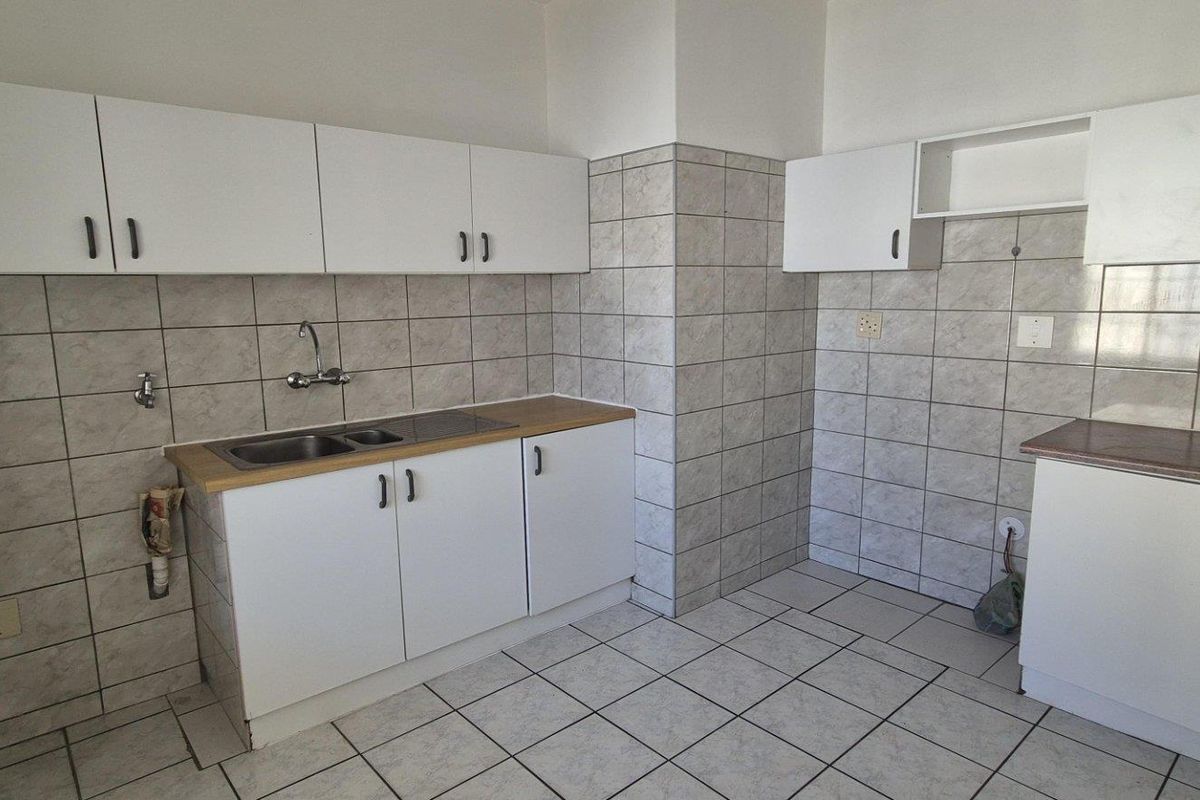 A functional kitchen featuring white built-in cabinetry, laminate countertops, tiled splashbacks, and tiled flooring, offering a clean and practical workspace.