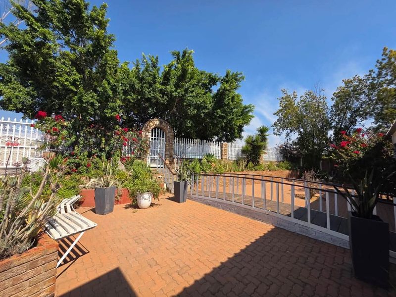 A spacious outdoor patio area featuring brick paving, a decorative stone archway, and secure perimeter fencing, ideal for outdoor relaxation.