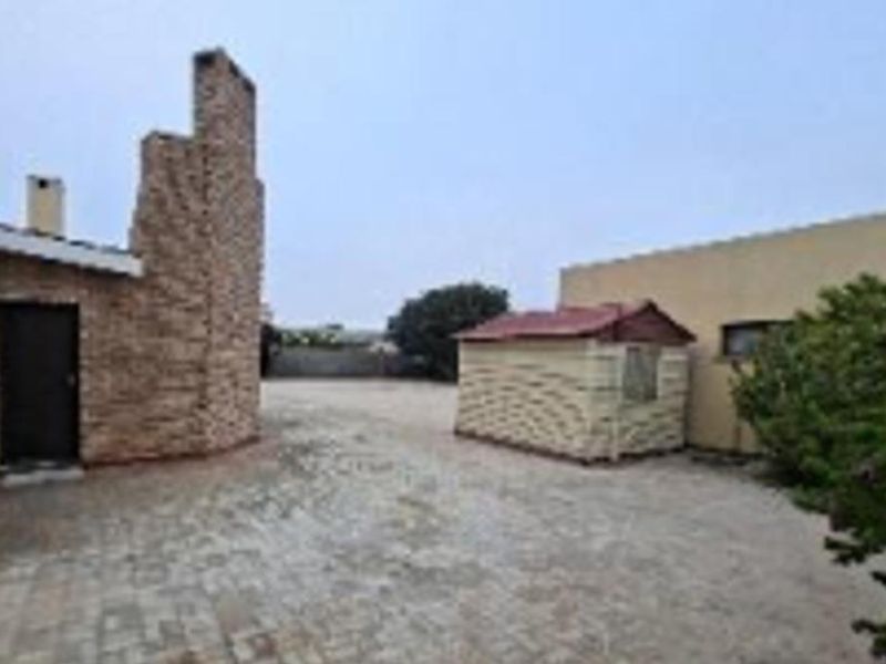 A rear courtyard area featuring paved ground, a prominent brick chimney structure, and a small detached storage shed.