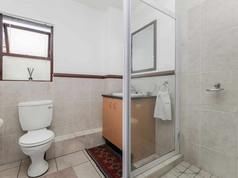 A functional bathroom featuring a shower enclosure, vanity cabinet with basin, and tiled finishes throughout.