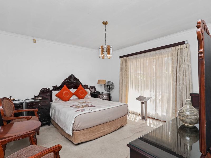 A spacious bedroom featuring neutral carpeting, a central light fixture, and large windows dressed with curtains, offering a comfortable and functional living space.