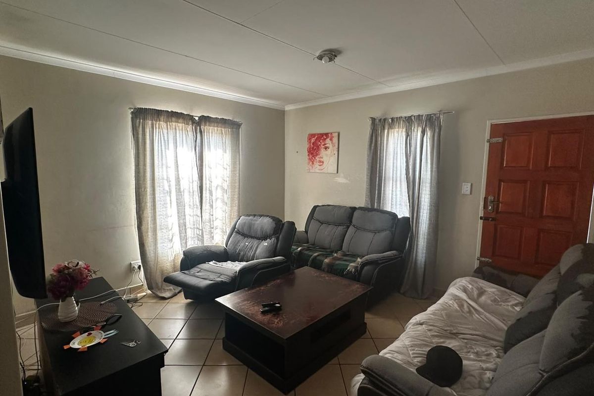 A functional living room featuring tiled flooring, coved ceilings, and a solid timber entrance door, providing a comfortable and practical living space.