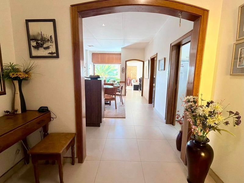 A bright, tiled hallway featuring a prominent timber archway leading into the main living and dining areas of the home.