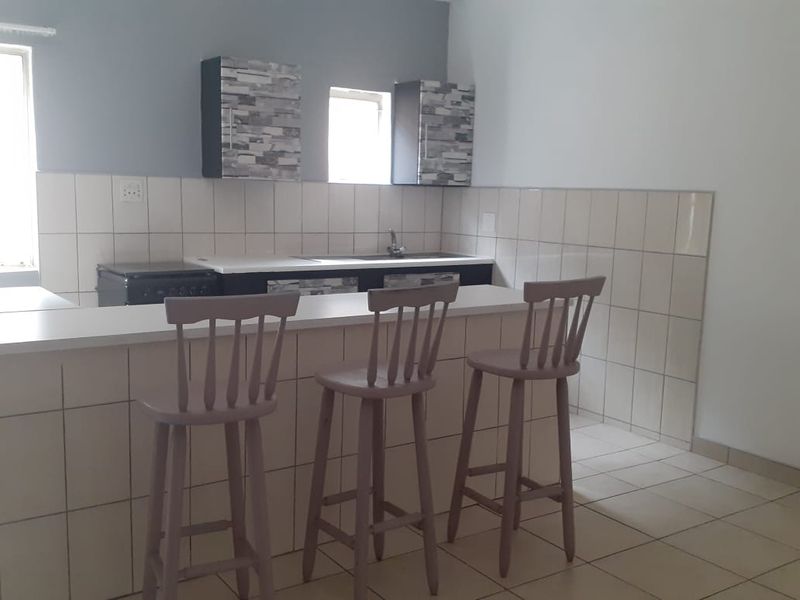 A functional kitchen area featuring tiled splashbacks, built-in cabinetry, a kitchen sink, and a breakfast bar counter.