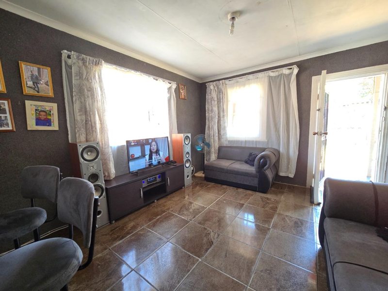 A living room featuring tiled flooring and coved ceilings, providing a functional space with natural light from multiple windows.