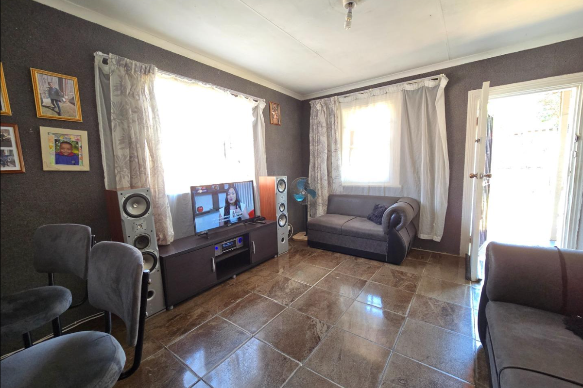 A living room featuring tiled flooring and coved ceilings, providing a functional space with natural light from multiple windows.