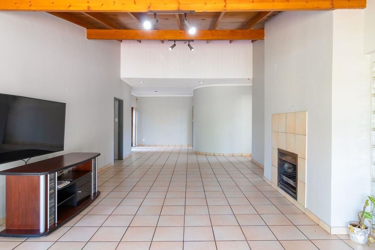 Spacious living area featuring exposed timber ceiling beams, tiled flooring, and a built-in fireplace with a glass block feature wall.