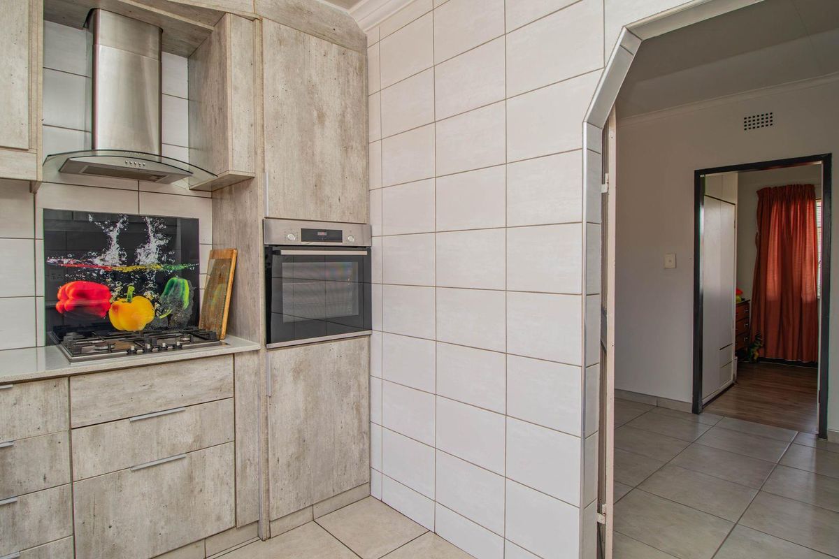 A functional kitchen featuring built-in cabinetry, a stainless steel extractor fan, integrated oven, and gas hob with a decorative splashback.