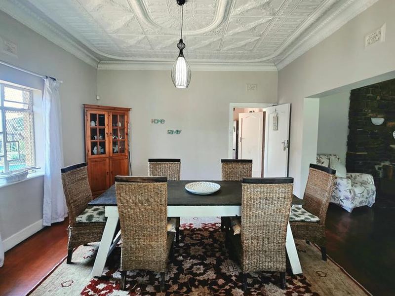 Elegant dining room featuring a classic ornate pressed metal ceiling, polished hardwood timber flooring, and a distinctive stone feature wall.