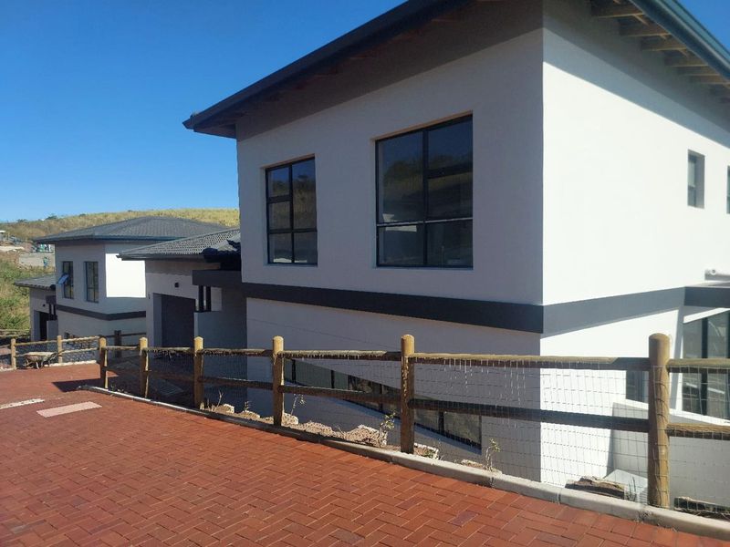 Modern two-story residential property featuring a clean rendered facade, dark aluminium window frames, and a paved driveway with timber fencing.