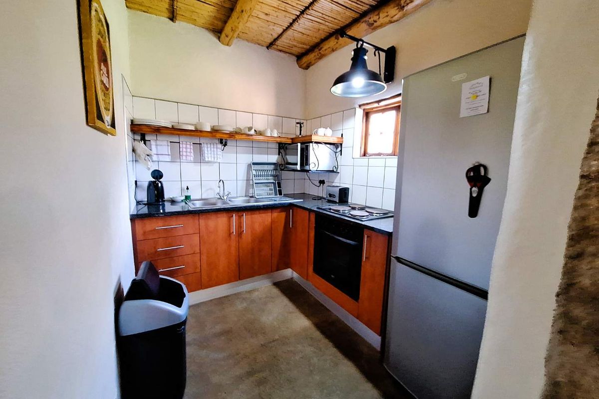 A rustic kitchen featuring wooden beam ceilings, tiled backsplash, built-in cabinetry, and integrated cooking appliances, offering a warm and functional prep space.