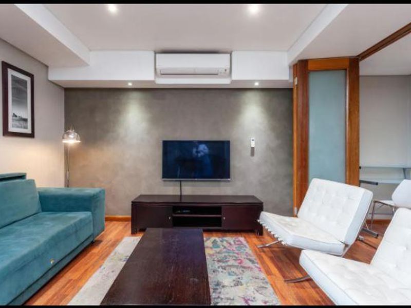 A well-maintained living room featuring hardwood flooring, a feature wall, recessed lighting, and a wall-mounted split-system air conditioner.