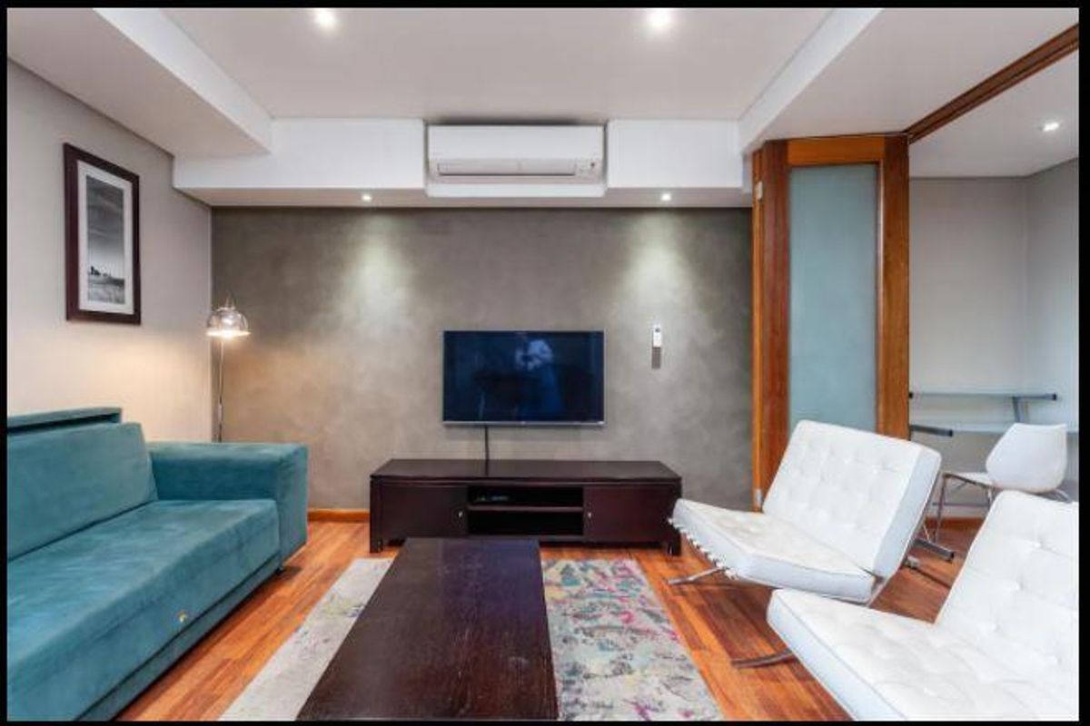 A well-maintained living room featuring hardwood flooring, a feature wall, recessed lighting, and a wall-mounted split-system air conditioner.