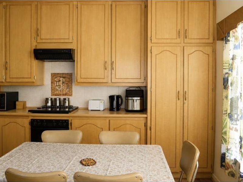 A functional kitchen featuring extensive light wood cabinetry, a built-in oven, hob, and extractor fan with a tiled backsplash.