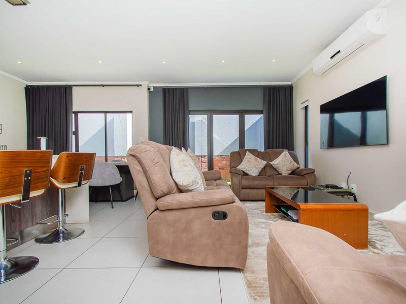 Spacious open-plan living area featuring tiled floors, recessed lighting, a split-system air conditioner, and seamless access to the outdoor space through sliding glass doors.