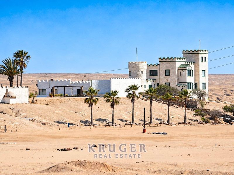 A unique castle-style residential property situated in a desert landscape, featuring distinctive turrets and parapet walls.