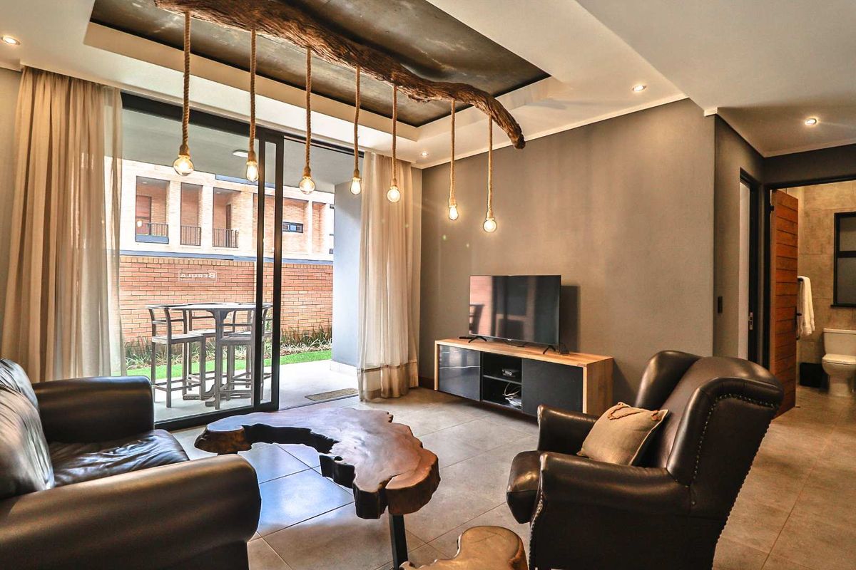 Modern living room featuring tiled flooring, recessed ceiling detail, and large sliding glass doors opening onto a private patio area.