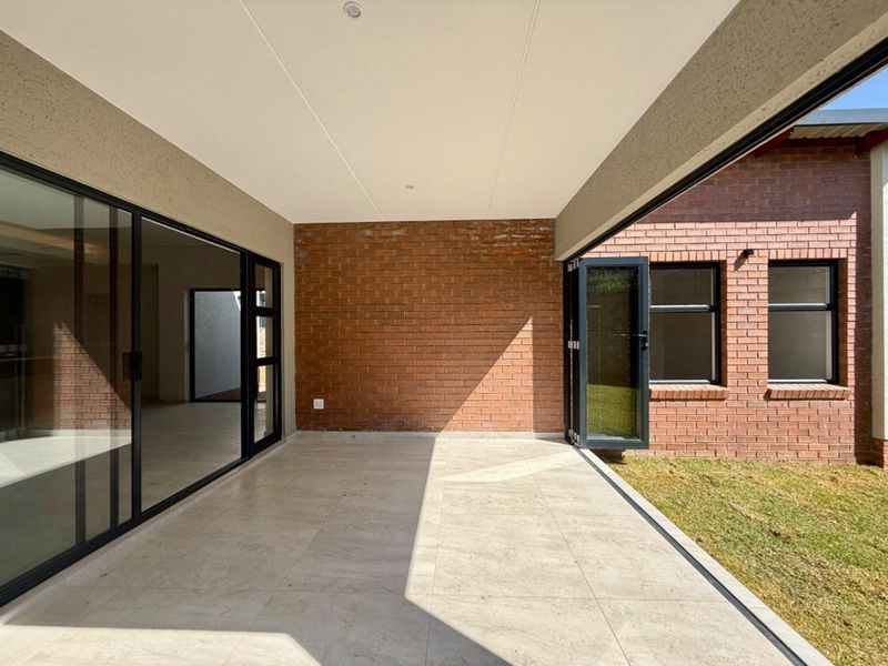 A modern covered patio featuring tiled flooring, exposed brick accents, and large aluminium sliding and folding doors providing seamless indoor-outdoor flow.