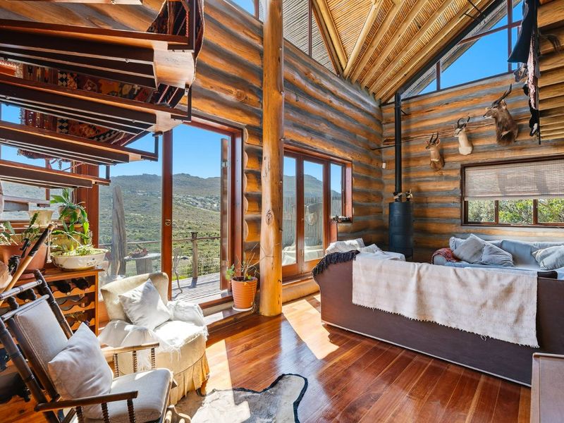 Rustic living room featuring exposed log walls, high vaulted timber ceilings, hardwood floors, and a wood-burning stove with expansive mountain views.