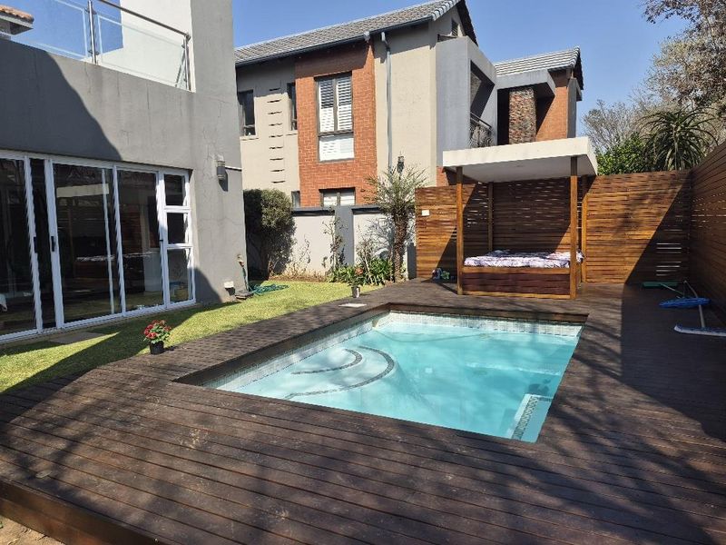 Private rear garden featuring a swimming pool, timber decking, and a covered outdoor gazebo area, accessible via large sliding glass doors.