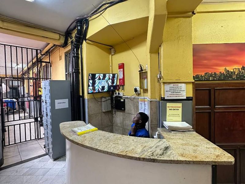 Building entrance and reception area featuring a curved granite-topped desk, security gate, and CCTV monitoring station.