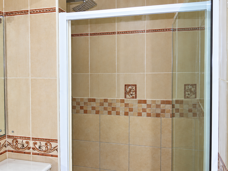 A bathroom featuring a shower enclosure with a rain shower head and decorative tiled walls.