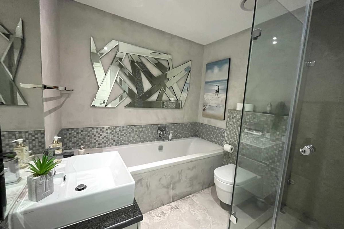Modern bathroom featuring a built-in bathtub, glass-enclosed shower, contemporary vessel sink, and decorative mosaic tile accents.
