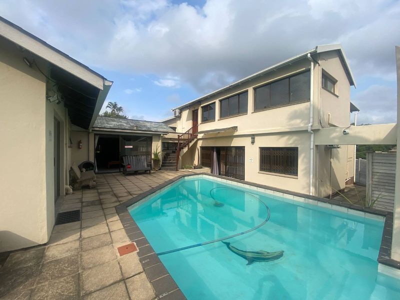 Outdoor pool area featuring a paved patio, external staircase, and multi-level building access, providing a functional space for outdoor recreation.