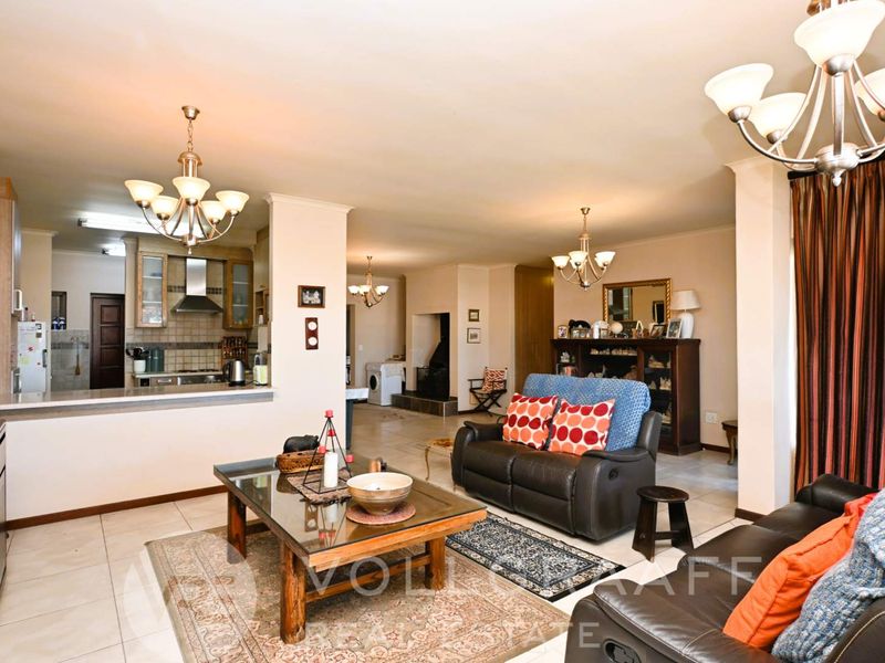 Spacious open-plan living area featuring tiled floors, a functional kitchen with built-in cabinetry, and a cozy fireplace, creating a versatile family living space.