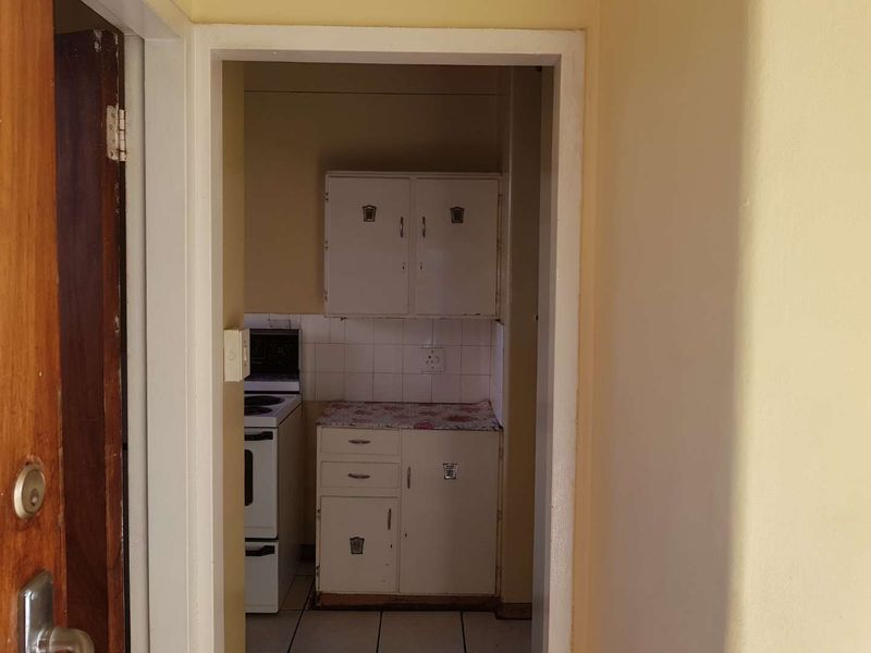 A compact kitchen featuring dated built-in cabinetry, tiled flooring, and a freestanding stove, offering potential for modernization and renovation.