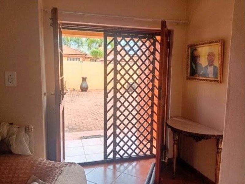 Living area featuring tiled flooring and double french doors opening onto a paved outdoor patio space with a security gate.