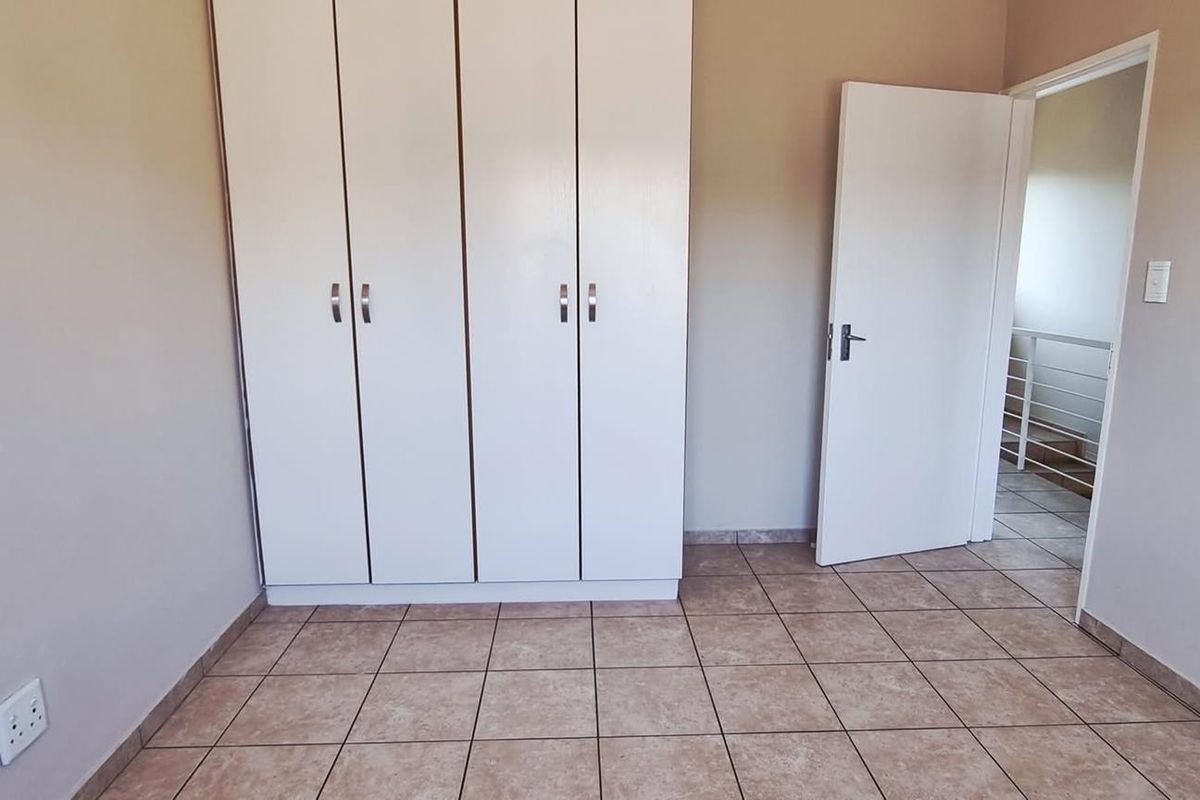 A clean, empty bedroom featuring neutral tiled flooring and built-in white cabinetry, offering a versatile space ready for personalization.