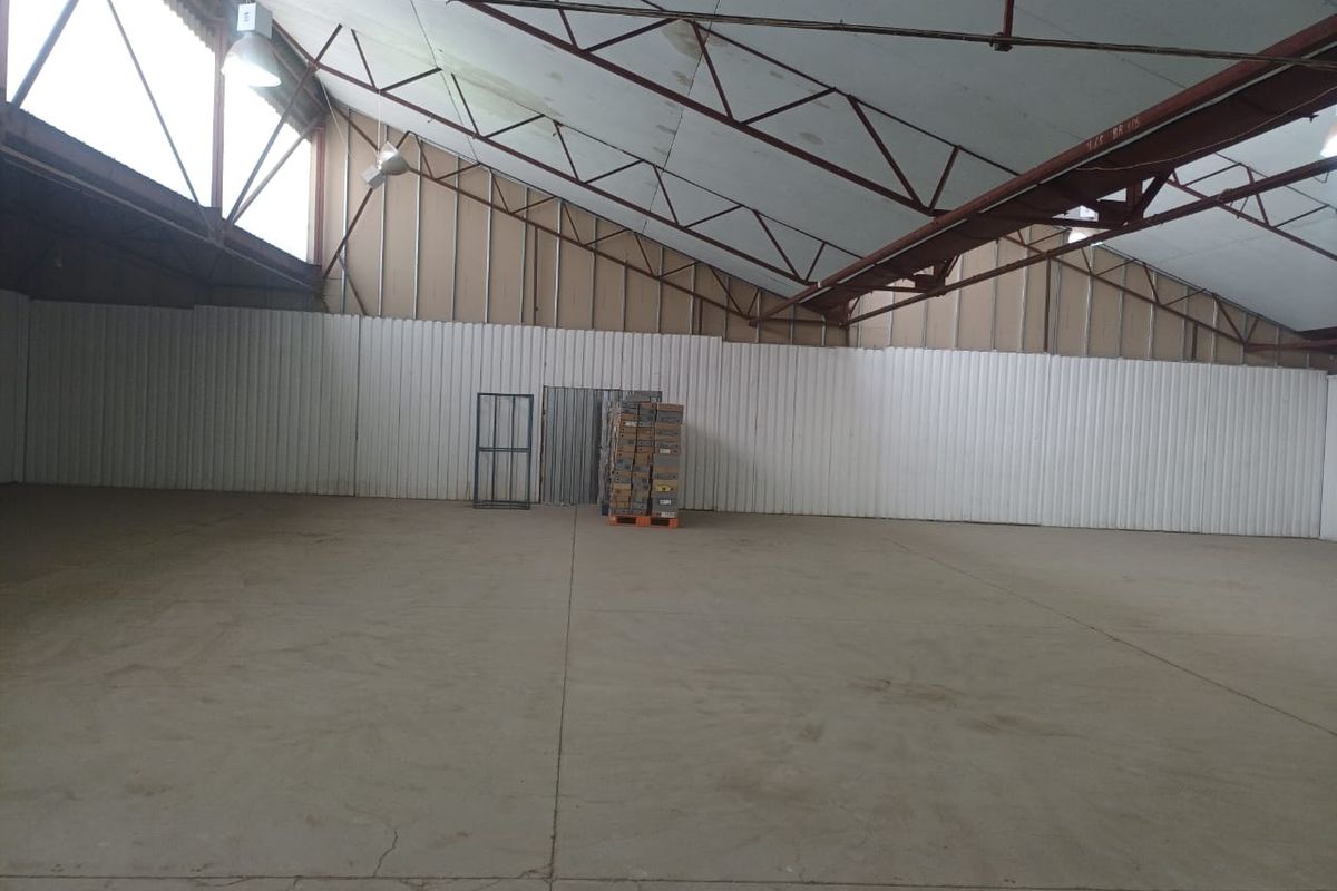 Spacious industrial warehouse unit featuring high ceilings with exposed steel trusses, corrugated metal walls, and durable concrete flooring.