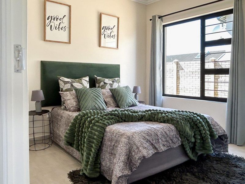 A well-maintained bedroom featuring neutral tiled flooring and a large aluminium-framed window providing natural light.