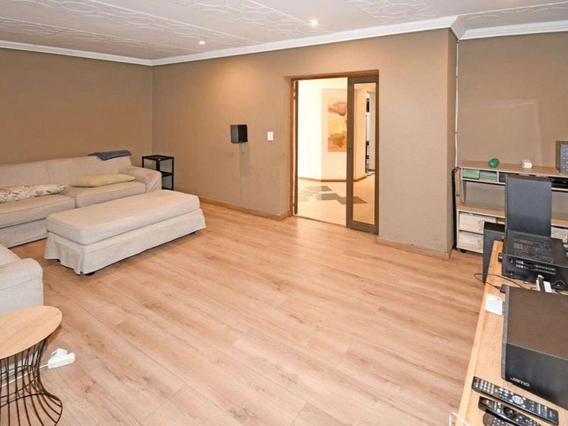 A living room featuring light-toned laminate flooring, a textured ceiling with recessed lighting, and a sliding door leading to an adjacent space.