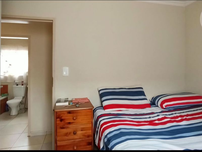 A bedroom featuring neutral wall finishes and direct access to an en-suite bathroom with tiled flooring.