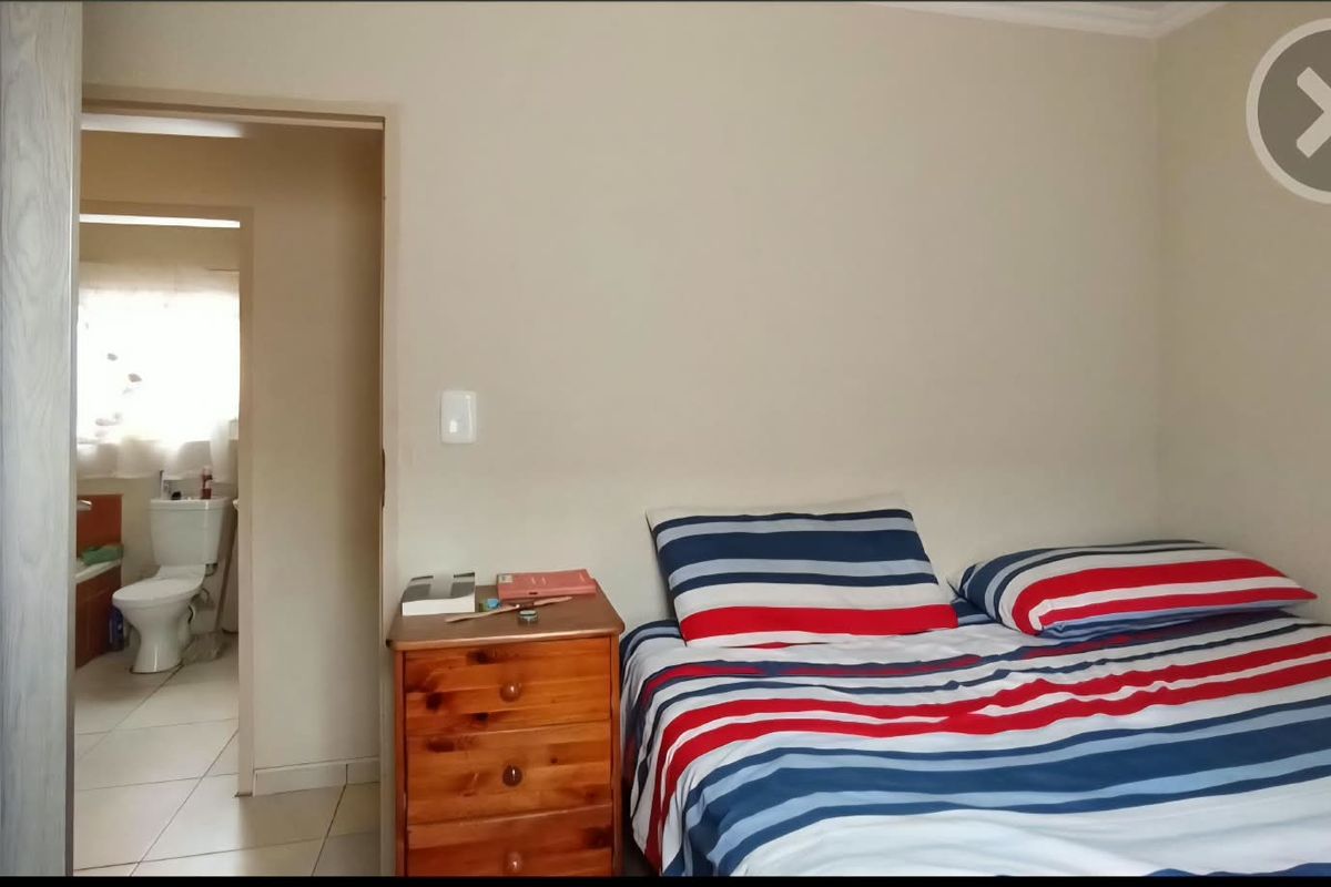 A bedroom featuring neutral wall finishes and direct access to an en-suite bathroom with tiled flooring.