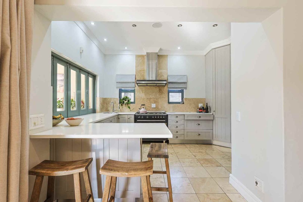 A well-appointed kitchen featuring stone countertops, built-in cabinetry, a gas stove with extractor fan, and tiled flooring, offering a functional and modern cooking space.