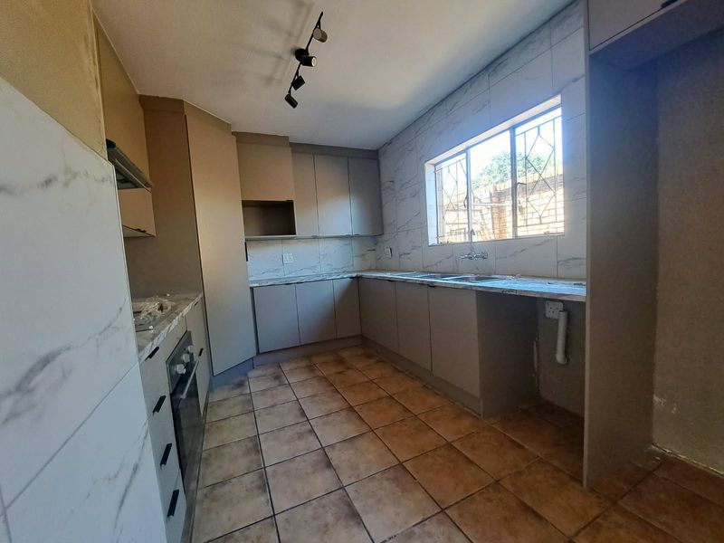 A functional kitchen featuring built-in cabinetry, marble-look tiled backsplash, built-in oven, and tiled flooring, offering a blank canvas for potential cosmetic updates.