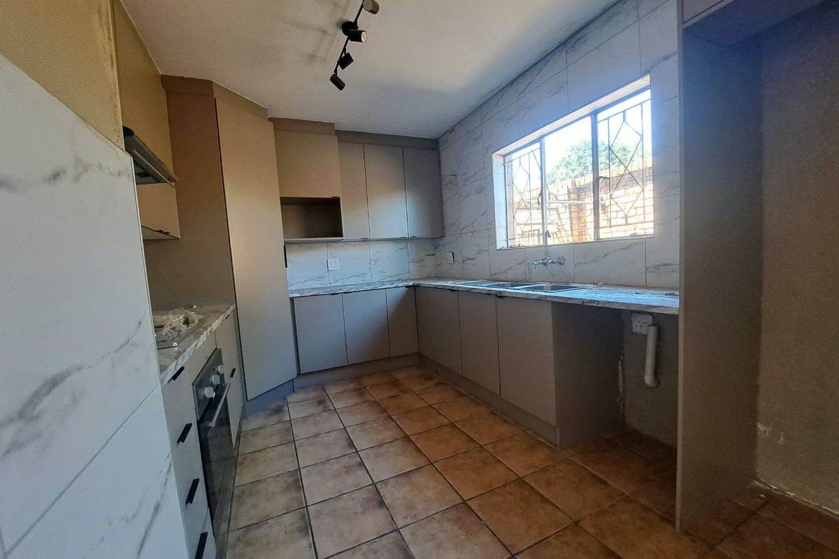 A functional kitchen featuring built-in cabinetry, marble-look tiled backsplash, built-in oven, and tiled flooring, offering a blank canvas for potential cosmetic updates.