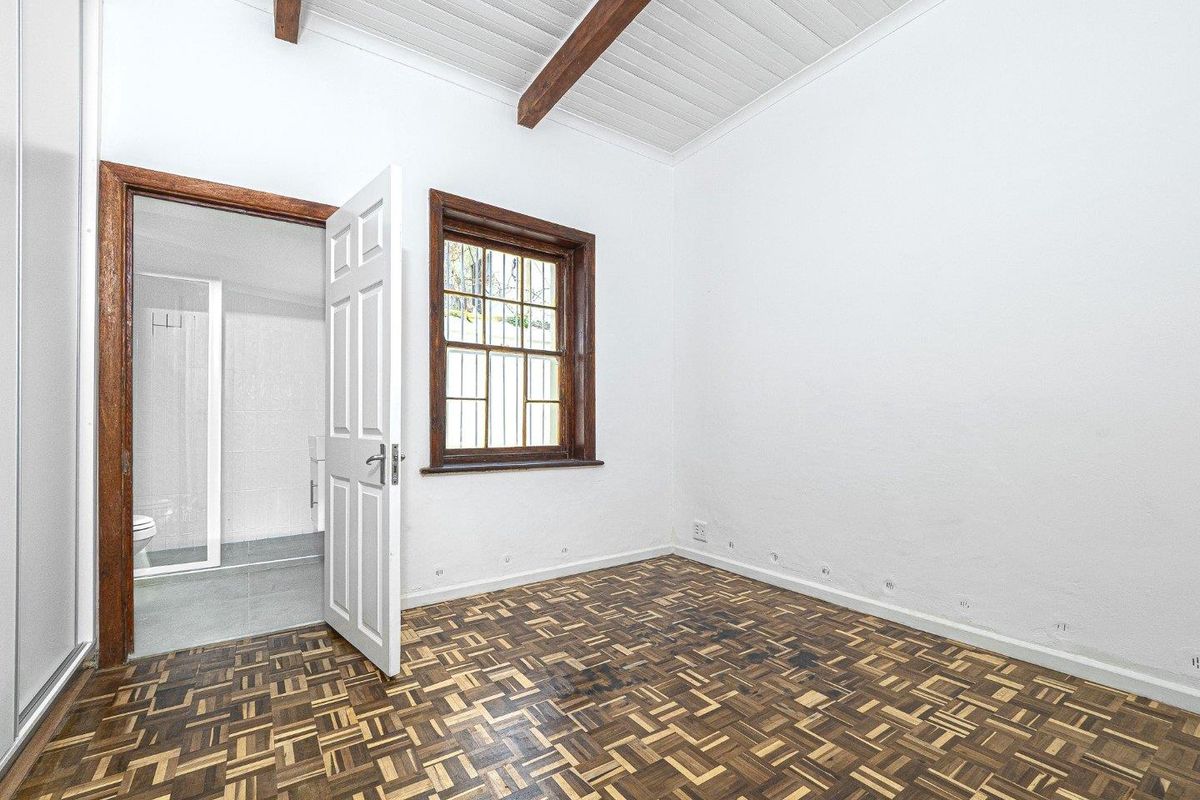 Empty bedroom featuring parquet flooring, exposed timber ceiling beams, and an en-suite bathroom access point.