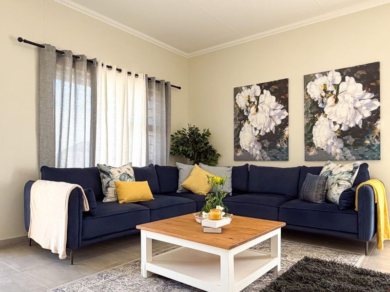 A well-maintained living room featuring neutral wall tones, tiled flooring, and coved ceiling details, providing a comfortable and inviting space.