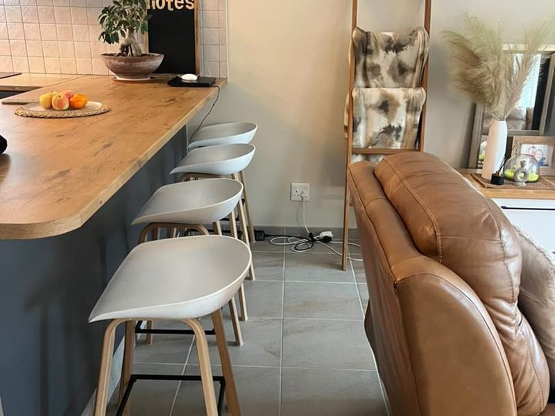 Open plan living area featuring a breakfast bar with a wooden countertop, tiled splashback, and neutral tiled flooring.