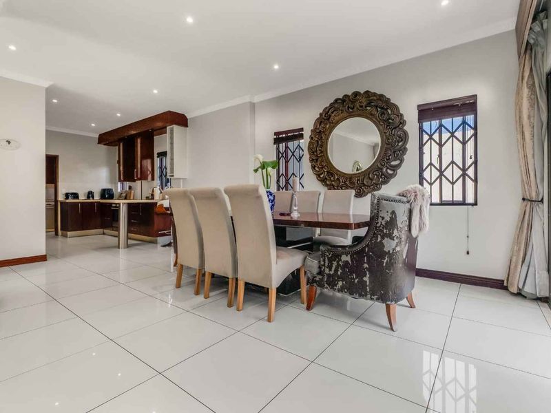 Spacious open-plan dining and kitchen area featuring polished porcelain floor tiles, recessed lighting, and direct access to the outdoor area via sliding glass doors.