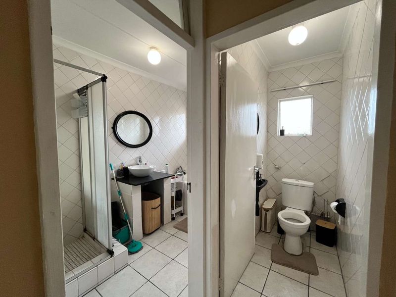 A functional bathroom featuring a separate shower enclosure, vessel sink vanity, and a private toilet area with tiled finishes throughout.