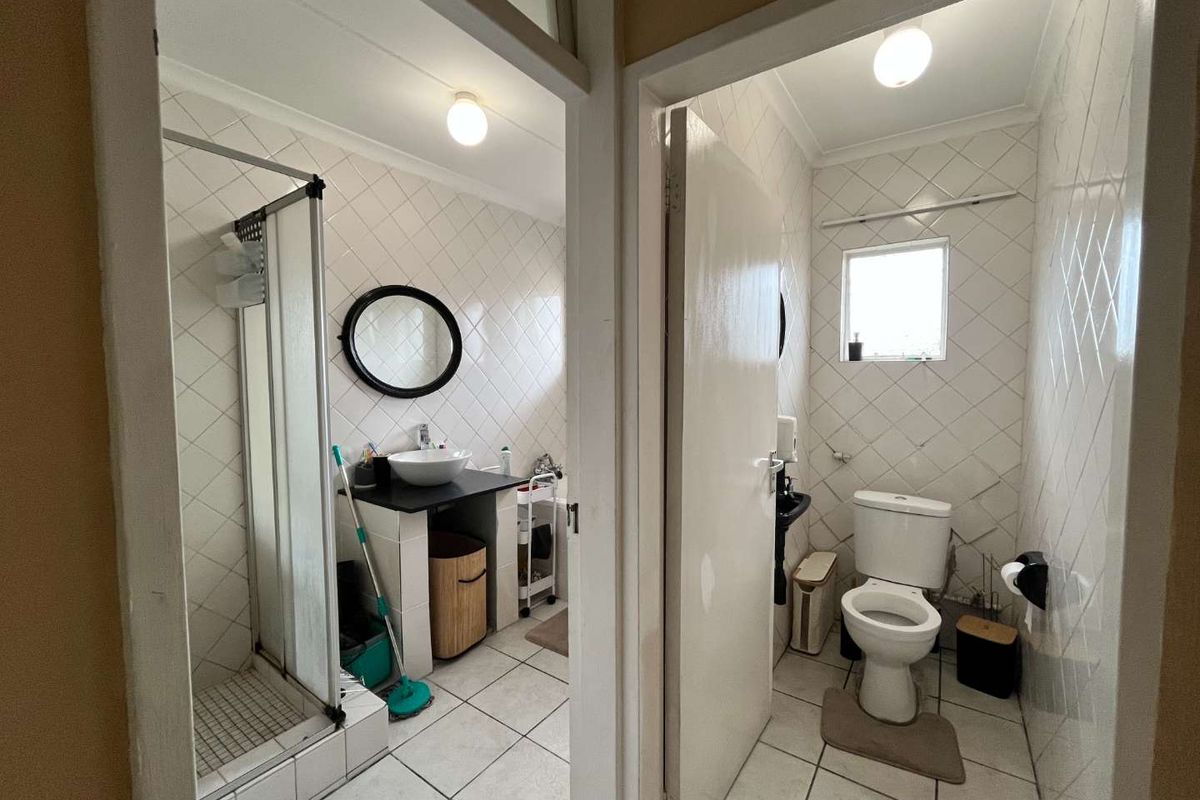 A functional bathroom featuring a separate shower enclosure, vessel sink vanity, and a private toilet area with tiled finishes throughout.