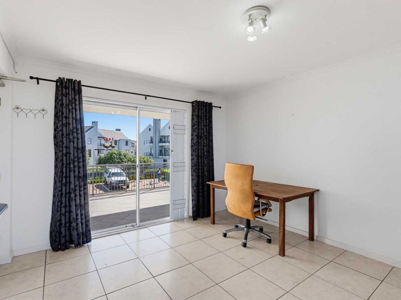 A bright living area featuring ceramic floor tiles and a large sliding glass door providing access to an outdoor balcony.