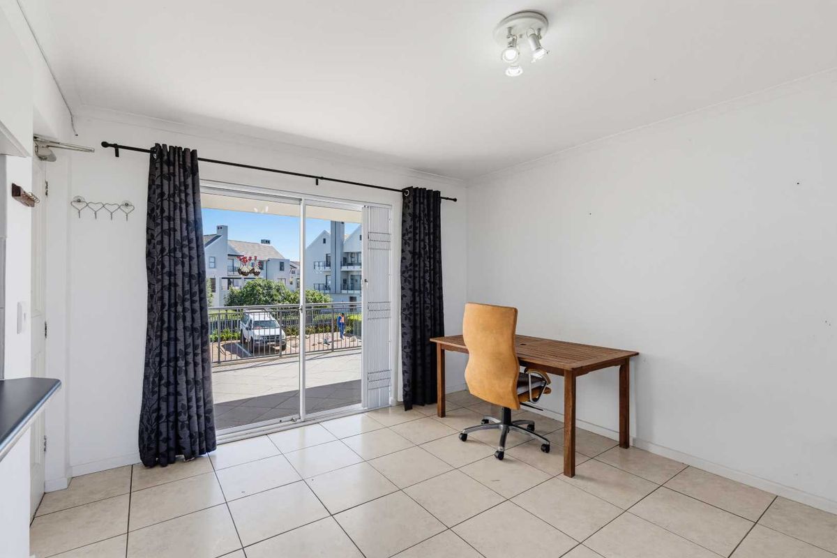 A bright living area featuring ceramic floor tiles and a large sliding glass door providing access to an outdoor balcony.